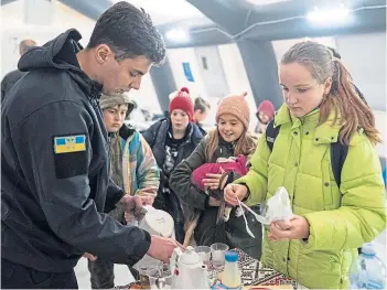  ?? ?? LIFELINE: A rescue worker makes tea for children at a heating tent in Bucha, Ukraine.