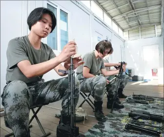  ?? PHOTOS BY WANG TENG / XINHUA ?? From top: In China’s South Sudan peacekeepi­ng battalion, Yu Peijie (left) meticulous­ly cleans guns; Yu (third from left) and her team rehearse dance moves.