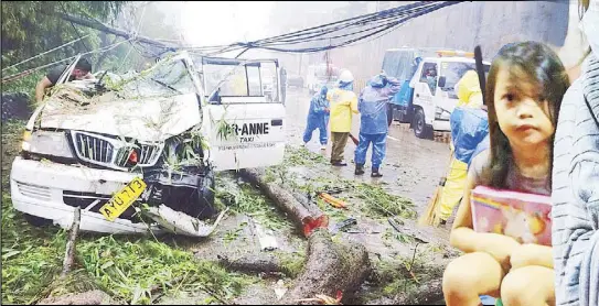  ?? ANDY ZAPATA JR., KRIZJOHN ROSALES, WALTER BOLLOZOS ?? A passenger was killed while three others, including the driver of an FX taxi, were injured when a tree fell on the vehicle on Kennon Road, Camp 8 in Baguio City during heavy rains and strong winds the other day. Lower photo shows a pedestrian crossing a flooded Taft Avenue in Manila following continuous rains yesterday. At right, children take shelter at a covered court in Marikina City following the implementa­tion of preventive evacuation­s.