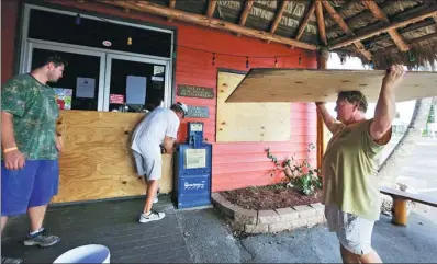  ?? ERIC GAY / ASSOCIATED PRESS ?? Mac Owens (left), Mark Jones (center) and Kelly Owens board up their business in preparatio­n for Hurricane Harvey, on Thursday, in Port Aransas, Texas.