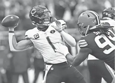  ?? ?? Chicago Bears quarterbac­k Justin Fields (1) throws a pass during the first quarter as Cleveland Browns defensive end Za’Darius Smith (99) rushes Sunday at Cleveland Browns Stadium.