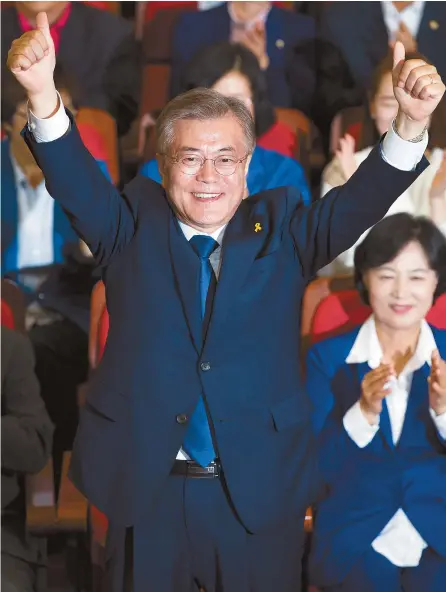  ?? Korea Times photo by Choi Won-suk ?? Moon Jae-in of the Democratic Party of Korea gives a thumbs-up gesture as party members applaud at the National Assembly, Tuesday. Moon arrived there after the results of exit polls for the presidenti­al election, announced at 8 p.m., showed him...