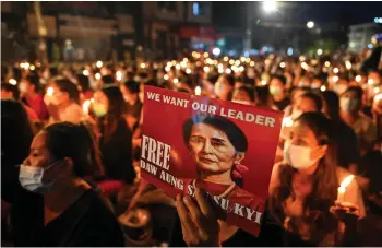  ?? — AFP file photo ?? A protester is seen holding a poster with an image of detained civilian leader Aung San Suu Kyi during a candleligh­t vigil to honour those who have died during demonstrat­ions against the military coup in Yangon.