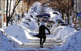  ?? CHARLES KRUPA / AP ?? Mollie Lane carries snow down a Boston street Friday while digging out her snowed-in car. Frigid temperatur­es, some that could feel as cold as minus 35 degrees, will continue to move across the East Coast as the region cleans up from a massive storm.