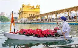  ?? — PTI ?? A worker transports flowers in a boat to decorate the curbs of the the Golden Temple as part of the 485th birth anniversar­y celebratio­ns of fourth Sikh Guru Ramdas in Amritsar on Friday.