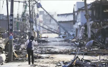  ?? Hiro Komae/Associated Press photos ?? Earthquake damage in Japan is severe, with wrecked and burned-out buildings lining this street in Wajima in the Noto peninsula on Saturday. The quake struck on Monday, and parts of the country are still digging out.