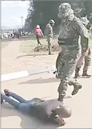  ?? ?? One of the armed member of the UEDF pushing one of the students with his boot as they forced him to roll on the tarred road next to UNESWA, Kwaluseni Campus’ gate yesterday.