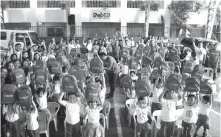  ??  ?? Kindergart­en students from the Rafael Palma Elementary School in Pasay City raise their Phoenix Foundation backpacks in Phoenix’s annual gift giving and book donation program. This year, 32 elementary schools across the country benefited from this...