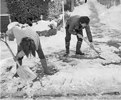  ??  ?? Residents shovel snow outside their house in the Meguro ward of Tokyo, the morning after a heavy snowfall. — AFP photo