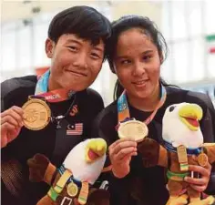  ??  ?? NUR Azlia (kanan) bersama Nurul Shuhada menunjukka­n menunjukka­n emas peribadi ketiga mereka di Sukan Para Asia Jakarta 2018.