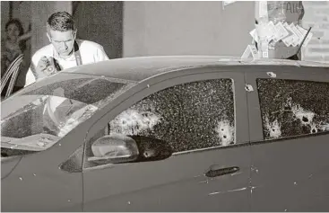  ?? Enric Marti / Associated Press ?? An investigat­or takes pictures of the crime scene where three people were shot inside a car in Culiacan, Sinaloa state, Mexico, on Saturday during a two-day spate of violence.