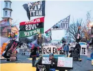  ??  ?? BARRICADES Workers board up businesses in Washington, where police have blocked off several streets for safety. Right, an anti-Trump protest in city