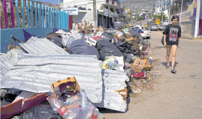  ?? FILE ?? A resident walks past debris more than two weeks after Hurricane Otis hit Acapulco, Mexico, as a Category 5 storm on November 13, 2023.