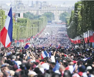  ?? THE ASSOCIATED PRESS ?? Tens of thousands waving French flags gather on the Champs-Elysées Avenue for a second day on Monday to welcome home their World Cup-winning soccer team.