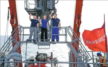  ?? LIU SHIPING / XINHUA ?? Crew members of China’s manned submersibl­e Jiaolong (from left) Tang Jialing, Zhang Yi and Shi Xuefa wave to colleagues aboard the ship Xiangyangh­ong09 after conducting a dive on Saturday during which a rock was brought up that could help explain the...