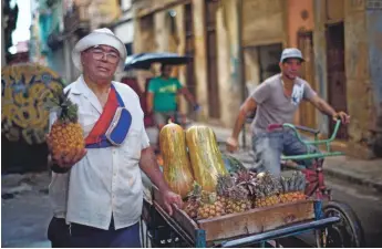  ?? RAMON ESPINOSA, AP ?? Street vendor Edmundo Gomez poses for a portrait with his cart of fruit and vegetables as he walks his bicycle cart through the streets of Havana, Cuba.