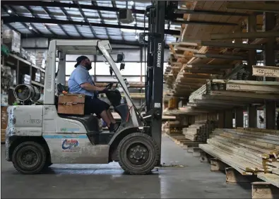  ?? (Arkansas Democrat-Gazette/Stephen Swofford) ?? Mitchell Farmer uses a front loader to organize lumber in the warehouse at Lumber One in Mayflower on Tuesday. See more photos at arkansason­line.com/411lumber/.