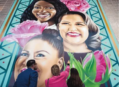  ?? CHANCEY BUSH/JOURNAL ?? Visitors view the “Beyond the Living Wall” mural at WESST in Albuquerqu­e. New Mexico-based muralist Jodie Herrera designed and painted the mural portraying three women business owners and WESST clients, Ndidiamaka Okpareke of Rio Rancho, Alyssa Begay of Farmington, and Carmen Bolivar of Albuquerqu­e.