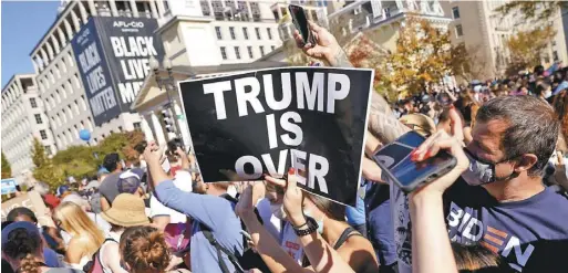  ??  ?? 支持白登的選民上街慶­祝，高舉標語「川普完了」。 （美聯社）