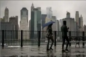  ?? CRAIG RUTTLE — THE ASSOCIATED PRESS ?? Passersby walk along the Promenade in the Brooklyn Heights neighborho­od as rain and clouds loom over lower Manhattan on the fifth anniversar­y of Superstorm Sandy Sunday in New York.