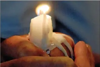  ?? NEW HAVEN REGISTER FILE PHOTO ?? The hot wax melts in the hands of a congregant during a candle service in a local church.