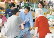  ?? Shohei Miyano / Associated Press ?? Prime Minister Shinzo Abe (center) listens to an evacuee during a visit to an evacuation center in Kurashiki city.