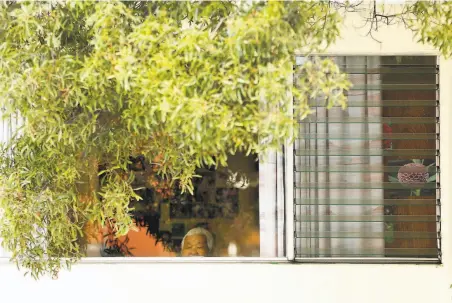  ?? Scott Strazzante / The Chronicle ?? A resident looks out a window at Central Gardens Skilled Nursing facility on Ellis Street in San Francisco, site of an outbreak.