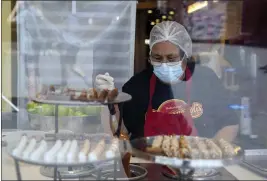  ?? MARCIO JOSE SANCHEZ — THE ASSOCIATED PRESS FILE ?? A worker wears a mask while preparing desserts at Universal City Walk in Universal City on May 14, 2021 .