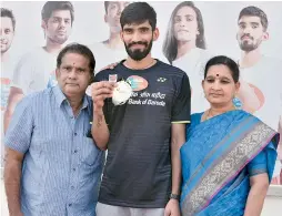  ?? — R. PAVAN ?? Srikanth Kidambi shows off his Denmark Open winner’s medal as he poses along with his parents at the Pullela Gopichand Badminton Academy in Hyderabad on Tuesday. Below: Srikanth shares a light moment with Hyderabad District Badminton president V....