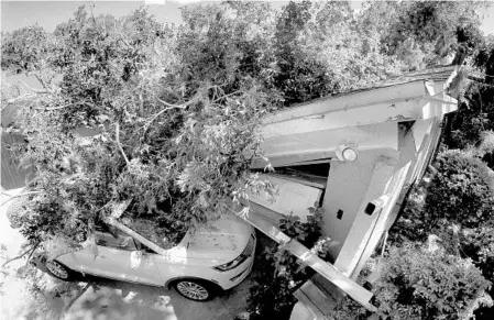  ?? JOE BURBANK/STAFF PHOTOGRAPH­ER ?? A tree — felled by the high winds of Hurricane Irma — rests atop a home and car Wednesday in the Maitland Isle neighborho­od of Maitand.