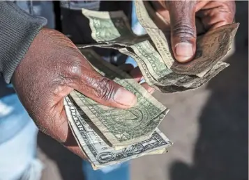  ?? ?? In demand: a currency exchange trader counts us dollar banknotes in Harare, Zimbabwe. the latest figures show hedge funds are still net short of us dollars. — bloomberg
