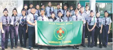  ??  ?? Kuching City Scout Council Commission­er Ng Ah Luke (second left) presents the flag to Lai (right) while other leaders and scouts look on.