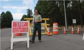  ?? Photograph: Felicia Fonseca/AP ?? Coconino national forest employee Amber Wong checks a road sign outside Flagstaff, Arizona, announcing the closure of the park amid extreme wildfire danger.