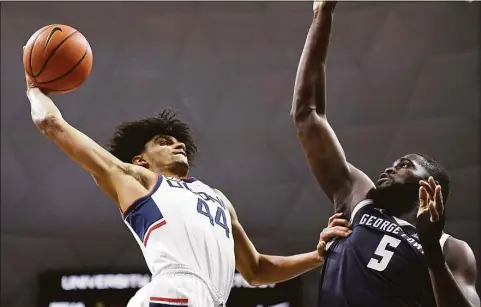  ?? Jessica Hill / Associated Press ?? UConn’s Andre Jackson winds up for a dunk as Georgetown’s Timothy Ighoefe (5) defends in the first half on Jan. 25.