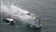  ?? (AP/Coast Guard Netherland­s/Kustwacht Nederland) ?? A boat hoses the smoke from a fire that broke out on a freight ship Wednesday in the North Sea, about 17 miles north of the Dutch island of Ameland.