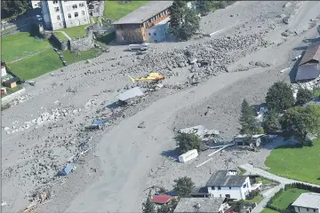  ??  ?? A rescue helicopter hovers over the Swiss village of Bondo after another landslide. — AFP photo