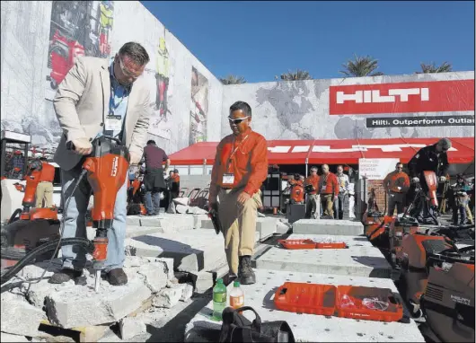  ?? K.M. Cannon Las Vegas Review-Journal file ?? Mathew Burns, left, of Jupiter, Fla., checks out a jackhammer with Hilti representa­tive Paul Adajar during the 2018 World of Concrete show at the Las Vegas Convention Center.
