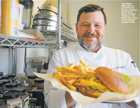  ??  ?? Chef Milton Villarrubi­a of Second Street Brewery displays his El Patron burger Tuesday afternoon. The burger has a blue corn enchilada stacked inside.