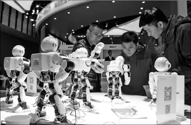  ?? CUI XIAO / FOR CHINA DAILY ?? Visitors interact with robots at the World Intelligen­t Manufactur­ing Summit in Nanjing, Jiangsu province.