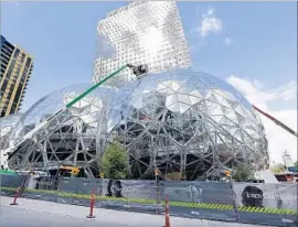  ?? Elaine Thompson Associated Press ?? THREE GLASS DOMES, shown under constructi­on in April, are part of Amazon’s growth in Seattle. The company is seeking a city for a second headquarte­rs.