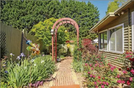  ?? REYNOLDS ROGERS FOR THE AJC ?? Homeowner Angela Green laid all the brick and stone work throughout her garden and built the red arches that let vines grow upward to the sunlight for her Cobb County garden.