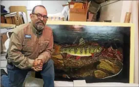  ?? PHOTO COURTESY OF ALBERTO REY ?? Steelhead fishing guide and angling artist Alberto Rey poses with a recent painting at his studio in Fredonia, N.Y.