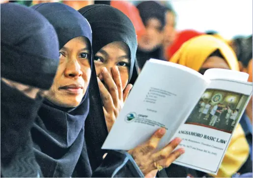  ??  ?? B.B.L. KNOWLEDGE – A group of Muslim women read from a booklet on the proposed Bangsamoro Basic Law (BBL) during a consultati­on hearing held at the Basilan State College in Basilan on Friday. (Jansen Romero)