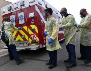  ?? ?? South Metro Fire Rescue firefighte­r Chris Herrington, left, opens the doors to an ambulance as, from left, John Cronin, Eric Szabo and Roxy Ligrani help each other put on their personal protective equipment as they arrive on a medical call in May 2020 in Littleton.