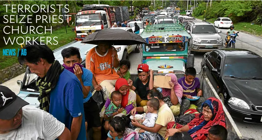  ?? —AFP ?? MASS EVACUATION Families fleeing Marawi City are caught in a traffic gridlock near a police checkpoint in Iligan City on Wednesday, a day after terrorists clashed with government forces.