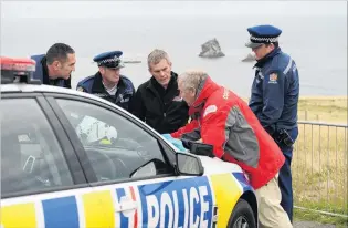  ?? PHOTOS: LINDA ROBERTSON ?? Action plan . . . Police and search and rescue personnel plan a search for a missing diver from the Sandfly Bay car park.