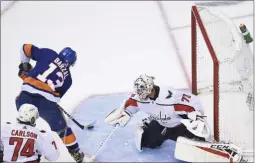  ?? NATHAN DENETTE ?? New York Islanders center Mathew Barzal (13) scores the winning goal past Washington Capitals goaltender Braden Holtby (70) as Capitals defenseman John Carlson (74) looks on during overtime.