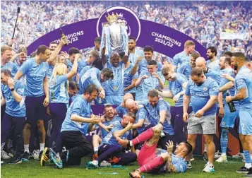  ?? MARTIN RICKETT AP ?? Manchester City’s Fernandinh­o lifts the Premier League trophy Sunday as he celebrates with teammates.