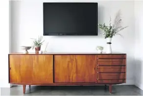  ??  ?? A mounted flat-screen mixes in nicely with mid-century modern teak credenza. “Making traditiona­l brown furniture relevant is all about context,” says Anna Brockway, co-founder of online marketplac­e Chairish.