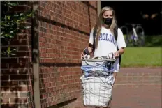  ?? Gerry Broome/Associated Press ?? Freshman Sarah Anne Cook carries her belongings on Tuesday as she packs to leave campus following a cluster of COVID-19 cases at the University of North Carolina in Chapel Hill.